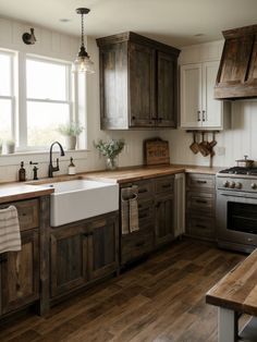 a kitchen with wooden cabinets and white walls, wood flooring, an apron style sink in the center