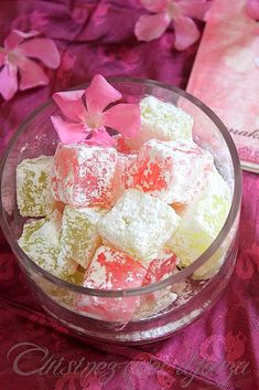 a glass bowl filled with pink and yellow marshmallows on top of a table