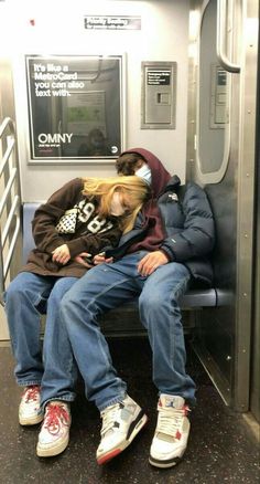 two people sleeping on a subway train next to each other with headphones in their ears