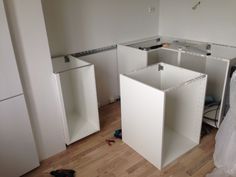 an unfinished kitchen with white cabinets in the middle and wood flooring on the other side