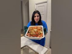 a woman holding a tray of cooked shrimp