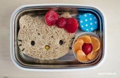 a hello kitty lunch in a bento box with strawberries and fruit on the side