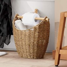 a wicker basket with toilet paper in it next to a chair and towel rack