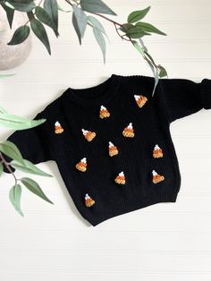 a black sweater with orange and white butterflies on it