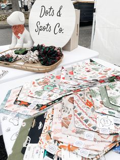 a table with lots of different types of cloths on it and a sign that says dots & spots co