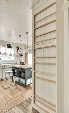 an open door leading to a kitchen with white cabinets and wood flooring on the walls