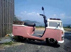 an old pink and white scooter parked on the side of the road next to a wooden fence