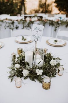 the table is set with candles, flowers and greenery for an elegant wedding reception