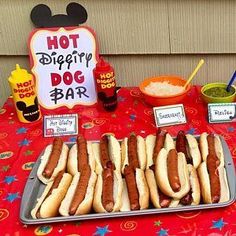 hot dogs on buns with toppings and condiments at a mickey mouse birthday party