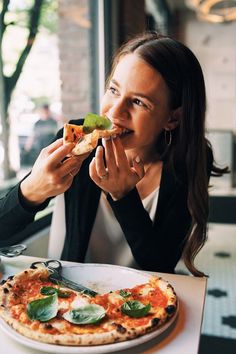 a woman sitting at a table eating pizza