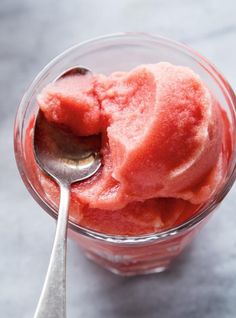 a spoon in a glass bowl filled with ice cream and watermelon sorbet