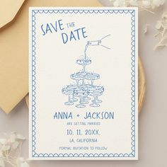 a save the date card on top of a table with flowers and envelopes next to it