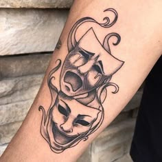 a tattoo with two masks on the arm