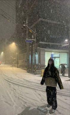 a woman walking down a snow covered street at night