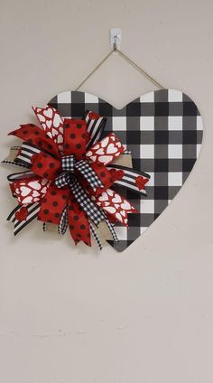 a heart hanging on the wall with a red and black checkered bow attached to it