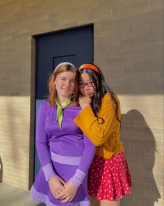 two young women standing next to each other in front of a door