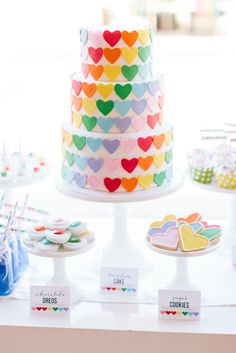 a multicolored cake sitting on top of a table next to other desserts