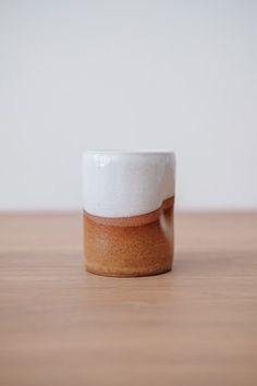 a white and brown cup sitting on top of a wooden table