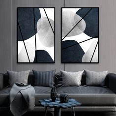 two black and white paintings hanging on the wall above a gray couch in a living room