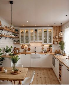 a kitchen filled with lots of wooden counter tops and white cupboards next to a dining room table