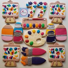 decorated cookies are arranged in the shape of art supplies