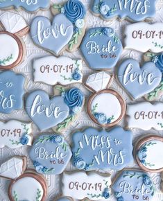 cookies decorated with blue and white frosting are arranged in the shape of hearts, roses, and letters