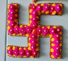 the letter f is decorated with pom poms and beads in pink, yellow, and orange