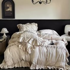 an unmade bed in a bedroom with a chandelier above it