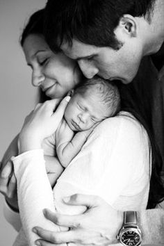 a man and woman holding a baby in their arms