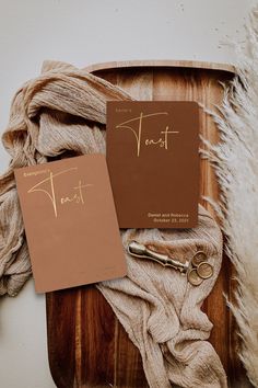 two notebooks on top of a wooden tray next to a pile of yarn and scissors