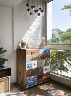 a room with a large window and a wooden dresser in it's centerpiece