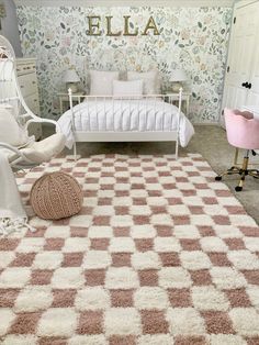 a white bed sitting in a bedroom next to a pink chair and rug on top of a floor