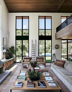 a living room filled with lots of furniture next to tall windows and a fire place