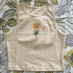 Crop top with sunflower embroidery.  Made of Cotton and Spandex. Tank Top Embroidery Ideas, Trendy Sleeveless Tops With Floral Embroidery, Fitted Cotton Tank Top With Floral Embroidery, Casual Embroidered Crop Top For Summer, Fitted Casual Crop Top With Floral Embroidery, Trendy Floral Embroidered Summer Tops, Trendy Floral Embroidery Summer Tops, Embroidered Fitted Casual Crop Top, Casual Embroidered Fitted Tank Top