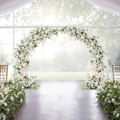 an outdoor ceremony setup with white flowers and greenery on the aisle, in front of a large window