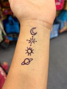 a woman's wrist tattoo with the sun, moon and stars drawn on it