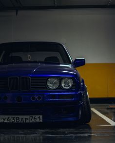 a blue car is parked in a parking garage with its hood up and lights on