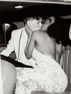 a man and woman kissing in the back of a car