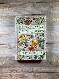 the folklore of trees and shrubs by laura c martin on a wooden table with wood planks