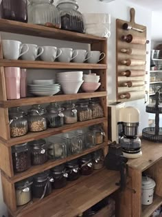 the shelves in this kitchen are filled with dishes and coffee maker's pots, mugs, and other items