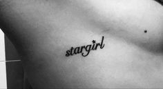 black and white photo of a woman's stomach with the word stargirl tattooed on it