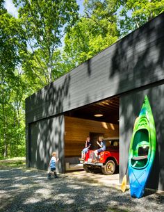 two kayaks are parked in front of a garage with the door open and people standing outside