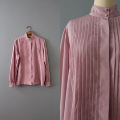 Vintage romantic essential minimalist secretary blouse in wisteria color. Pleated front, high neck, billowy sleeves. Silky polyester material. ⊰ Measurements: Fits like medium, large: 15" shoulders 42" bust 26" length 25" sleeves Tag: Dana Alexander Circa 1990s Condition: excellent! ⊰ Visit the shop: adriancompany.etsy.com ⊰ Instagram: @adriancovintage @the_veiled_ghost Formal Spring Shirt With Stand Collar, Formal Shirt With Stand Collar For Spring, Spring Office Tops With Stand Collar, Spring Stand Collar Blouse For Daywear, Elegant Top With Stand Collar, Stand Collar Blouse For Spring Daywear, Solid Color Blouse With Stand Collar For Work, Stand Collar Blouse For Daywear In Spring, Feminine Spring Blouse With Pintucks