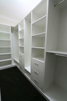 an empty walk in closet with white shelving and black carpeted flooring is shown