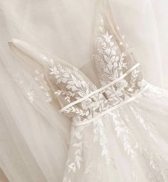 the back of a wedding dress with white flowers on it