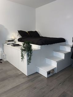 a bed sitting on top of a wooden floor next to a white shelf filled with books