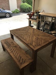 a wooden table and bench sitting in a garage next to a car parked on the street