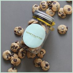 a jar filled with chocolate chip cookies sitting on top of a gray table next to a pile of blueberries