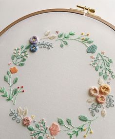 a close up of a embroidery on a hoop with flowers and leaves in the center