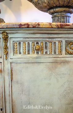 an antique dresser with marble top and gold details on the doors is shown in this image